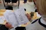 A woman looks at the colouring-in book which features a topless cowboy on the page.