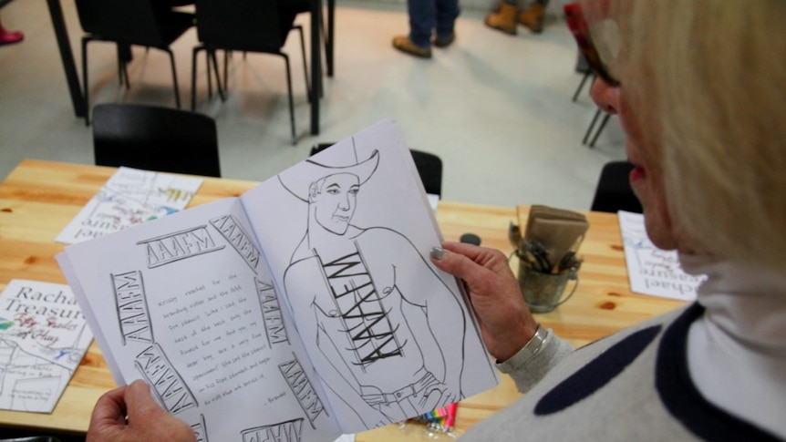 A woman looks at the colouring-in book which features a topless cowboy on the page.