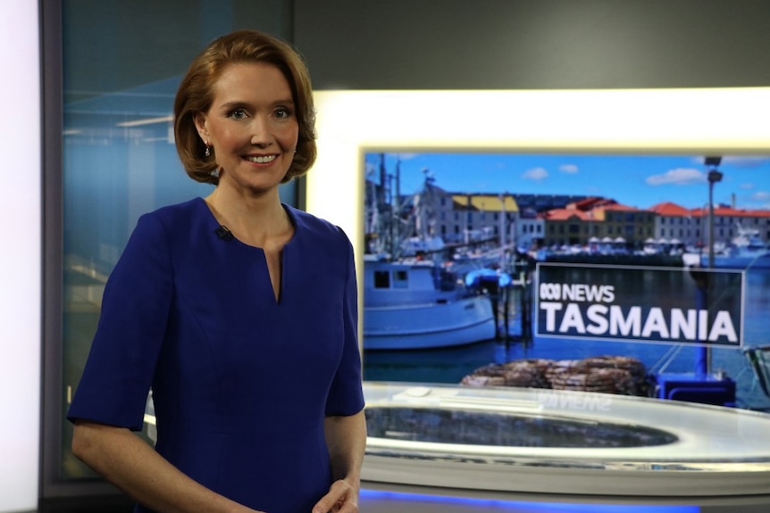 Ross standing in studio in front of screen saying ABC News Tasmania.