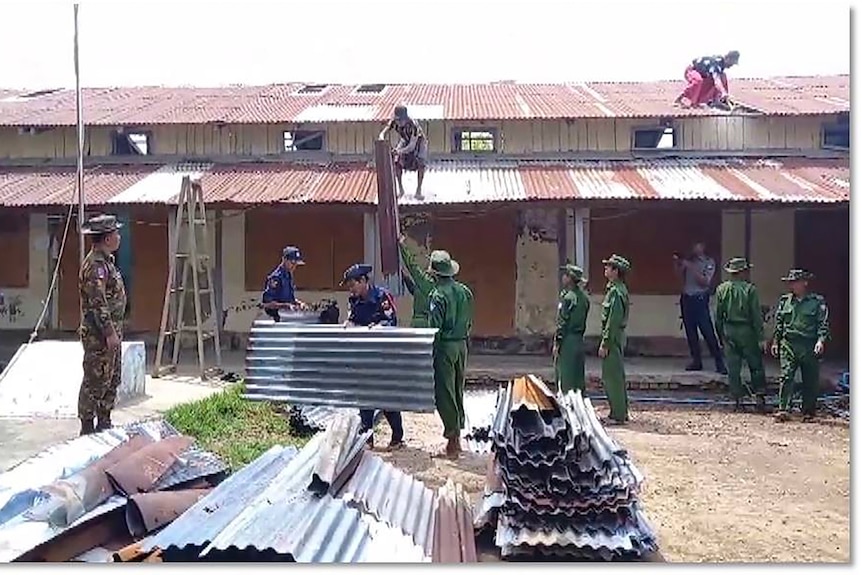 Soldiers and firefighters help repair a roof with corrugated iron sheets. 