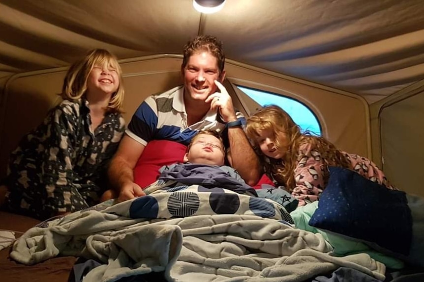 Kyran with his family in a tent.