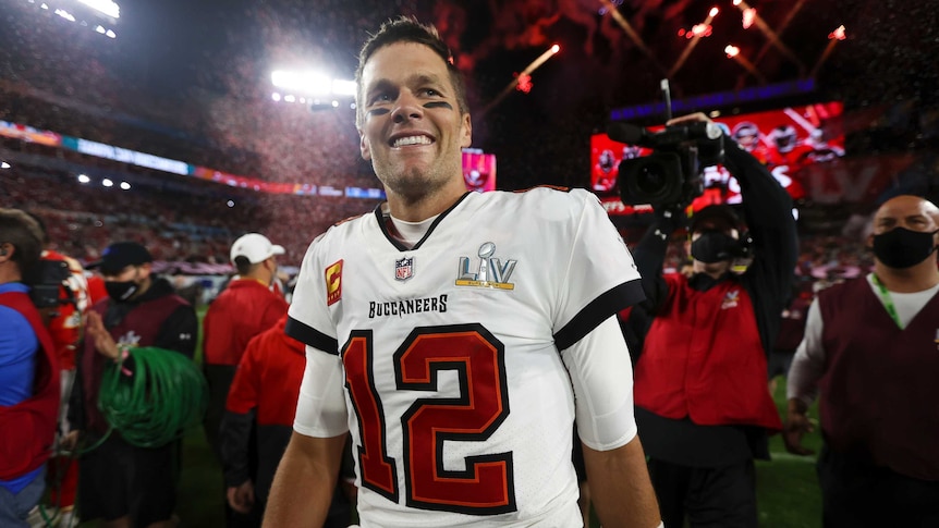 An NFL quarterback smiles as he walks on the field after his team wins the Super Bowl.