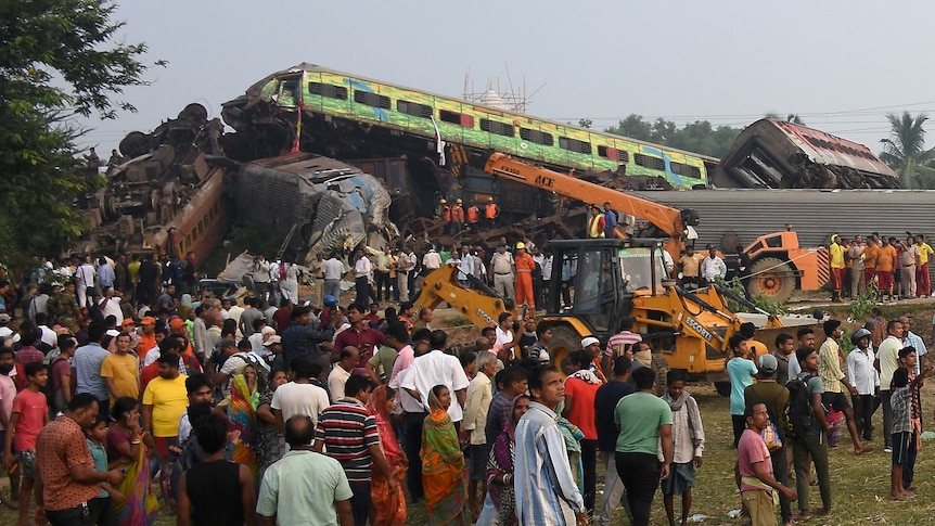 People stand next to damaged coaches after two passenger trains collided.