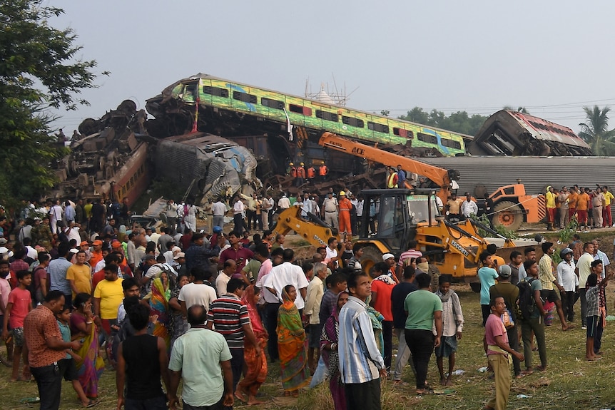 People stand next to damaged coaches after two passenger trains collided.