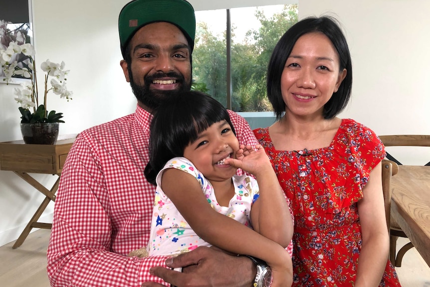 Vick Satgunasingam holds her daughter Oriana and sits next to his wife Marisse.