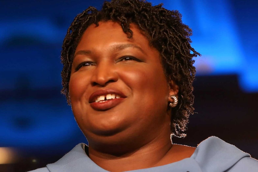 Stacey Abrams in a pale blue dress smiling