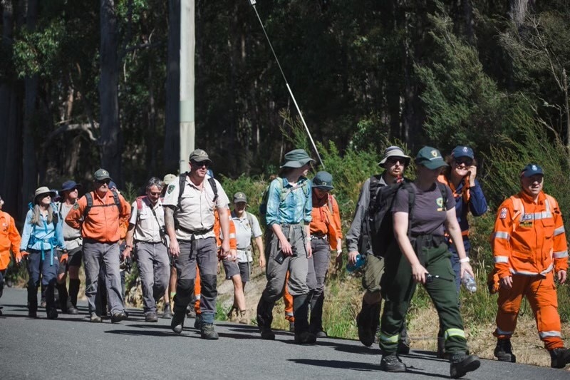 A group of emergency workers walk on the road in search of the girl.