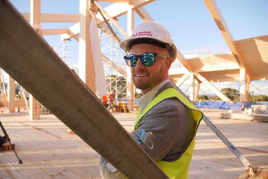 a man in a hardhat on the top floor of a wooden construction site