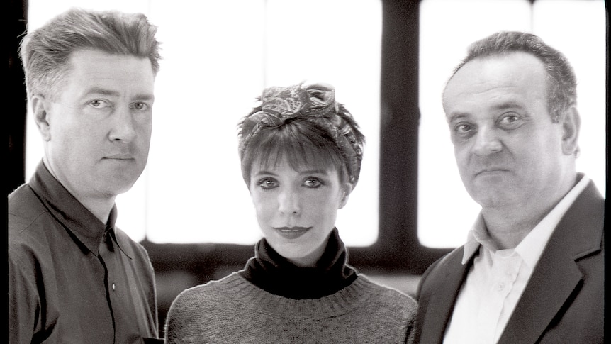 David Lynch, Angelo Badalamenti, and Julee Cruise stand side by side and smile at camera