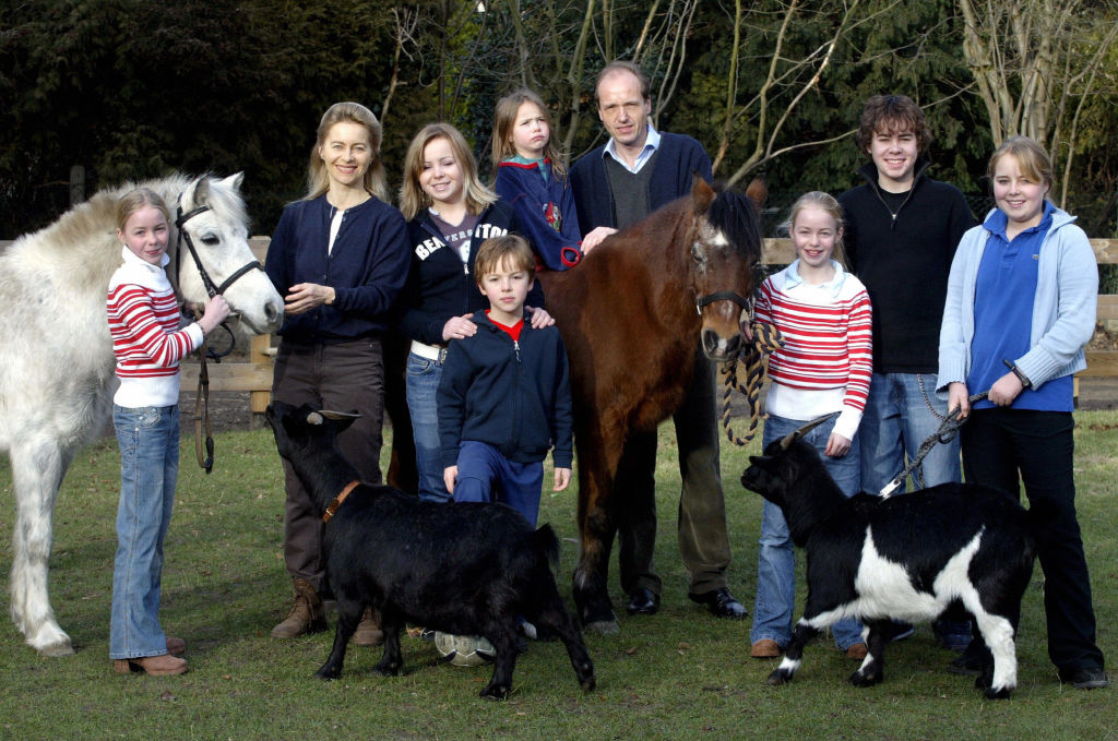Ursula von der Leyen and her husband Heiko pictured on a farm outdoors with their 7 children next to horses and goat.
