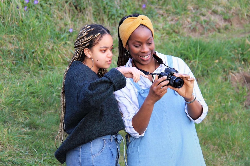 Melanie McCollin-Walker and her daughter Aaliyah look at a photo taken on a camera.