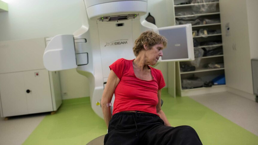 Sue Jensen lays herself out on the radiotherapy table for treatment.