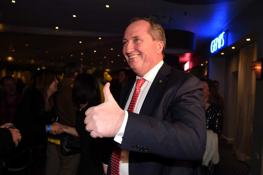Barnaby Joyce gives a thumbs up and smiles. He is in a restaurant surrounded by supporters.