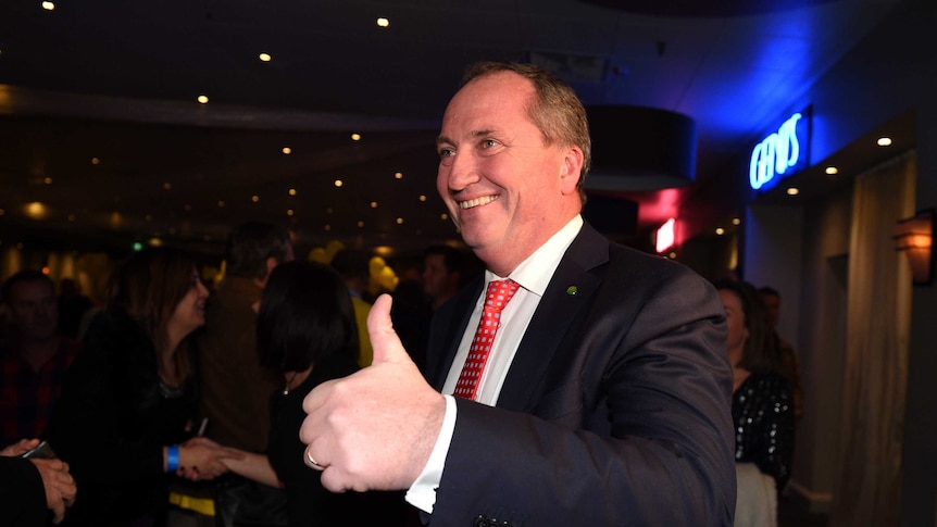 Barnaby Joyce gives a thumbs up and smiles. He is in a restaurant surrounded by supporters.