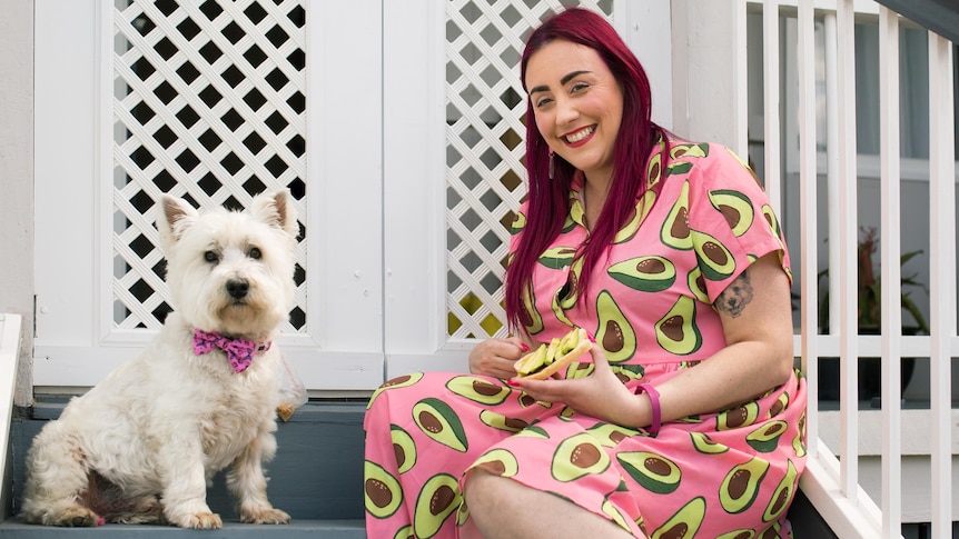 Melanie sitting on steps in an avocado print dress beside her white dog, in story about getting mortgage when working contracts.