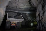 A large truck in a dark hole underground at MMG Dugald River mine