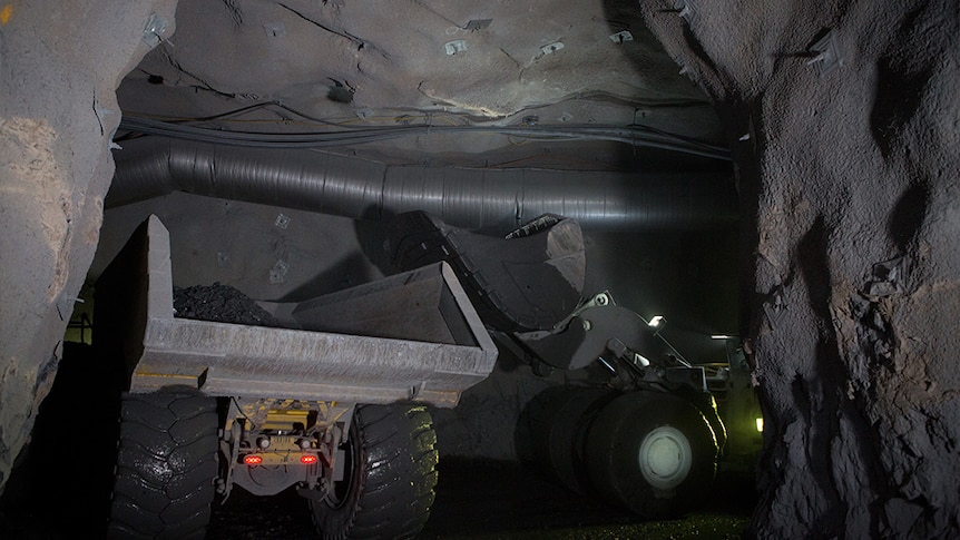 A large truck in a dark hole underground at MMG Dugald River mine