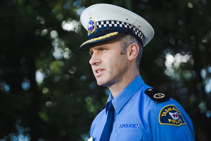 A police officer in a white hat looks to left of frame 