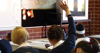 A girl raises her hand in a high school classroom.