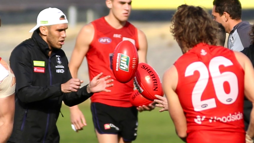 AFL footballer Harley Bennell marks a handball from a colleague during a training session.