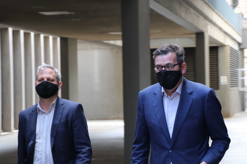 Victoria's Chief Health Officer Brett Sutton and Premier Daniel Andrews walking in suits and black masks.