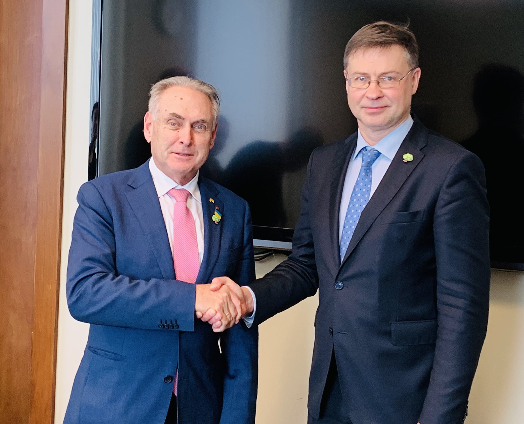 Man in blue suit shakes hands with another man in a navy suit