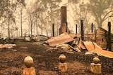 Building destroyed by bushfire with pots in foreground and kiln in background.