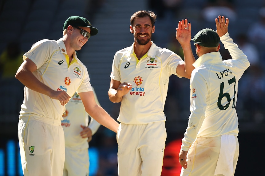 Mitch Starc smiles and high fives