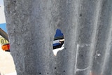 A hole in an asbestos fence opposite a primary school in WA 7 March 2013