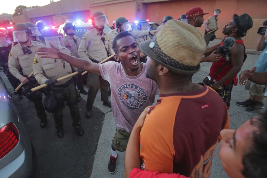 Protesters face off with police, as others try to block them during a rally in El Cajon in response to the police shooting.