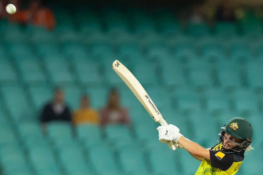 A cricket ball flies away from Australia batter Nicola Carey as she swings hard at the Twenty20 World Cup.