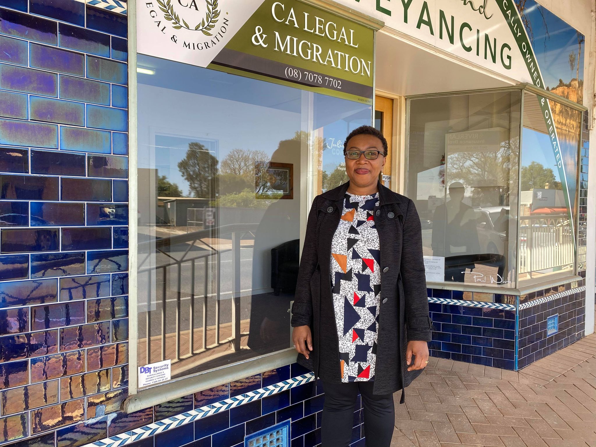 A woman stands in front of a business smiling.
