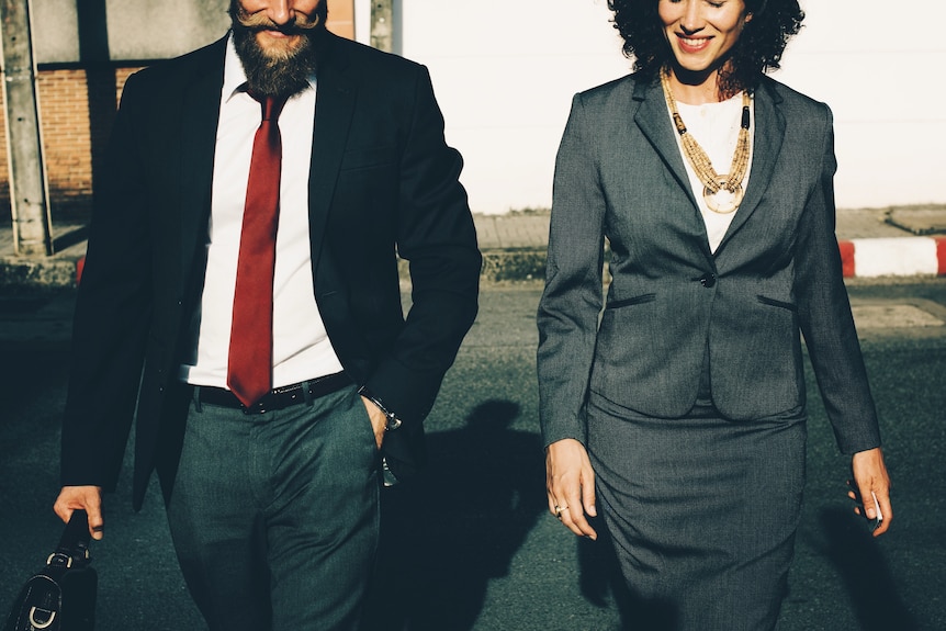 Woman and man in business clothes walking on the street to depict a professional mentor and mentee relationship.