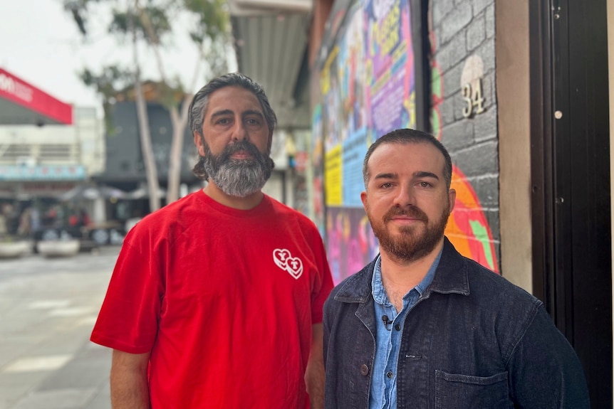 Man wearing a red t-shirt standing next to man in denim shirt and jacket in Footscray.