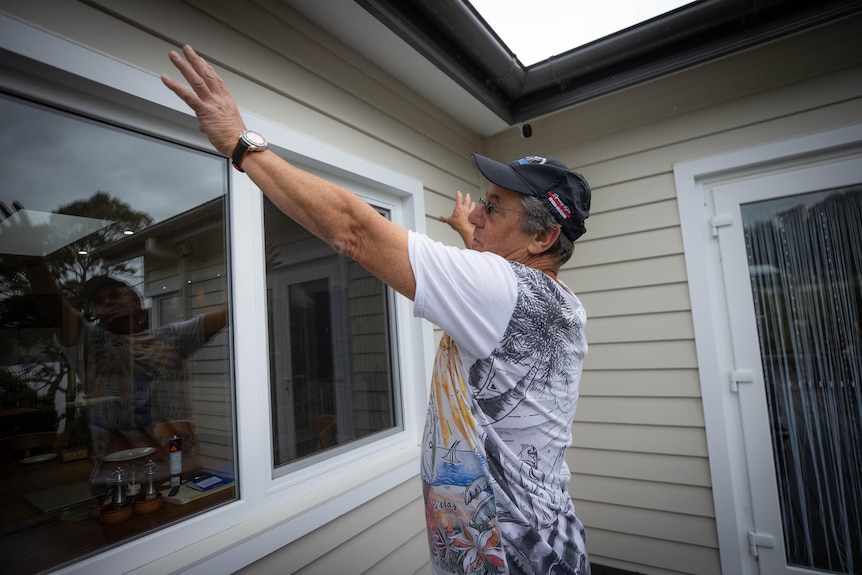 A man points to the roof of a house