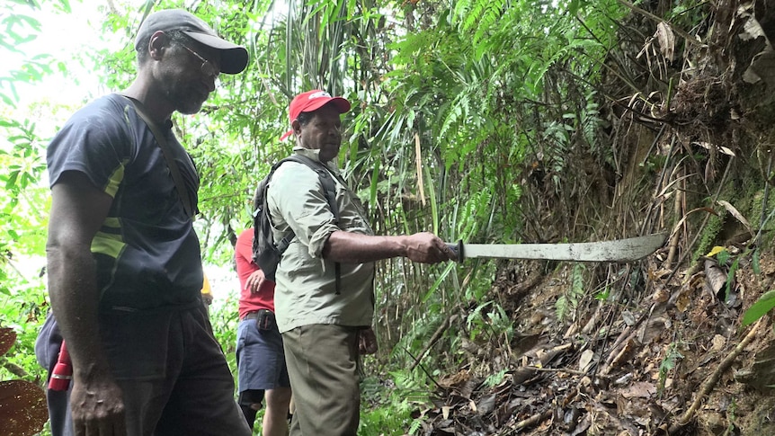 Landowner Rex Dowaka shows Nick Araho a section of Jap Road along the leafy Kokoda Track.