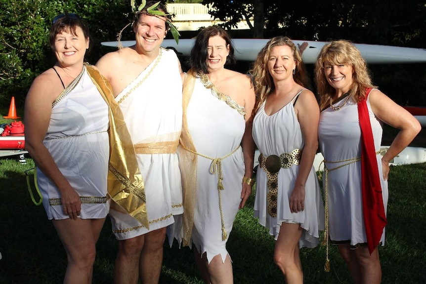Five people dressed in Greek togas with gold chains