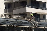 A worker stands on a Gold Coast building where two workers fell 26 storeys to their deaths.