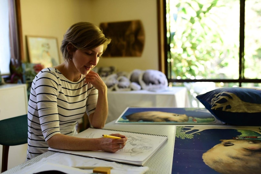 Woman sitting at table drawing in a sketch book