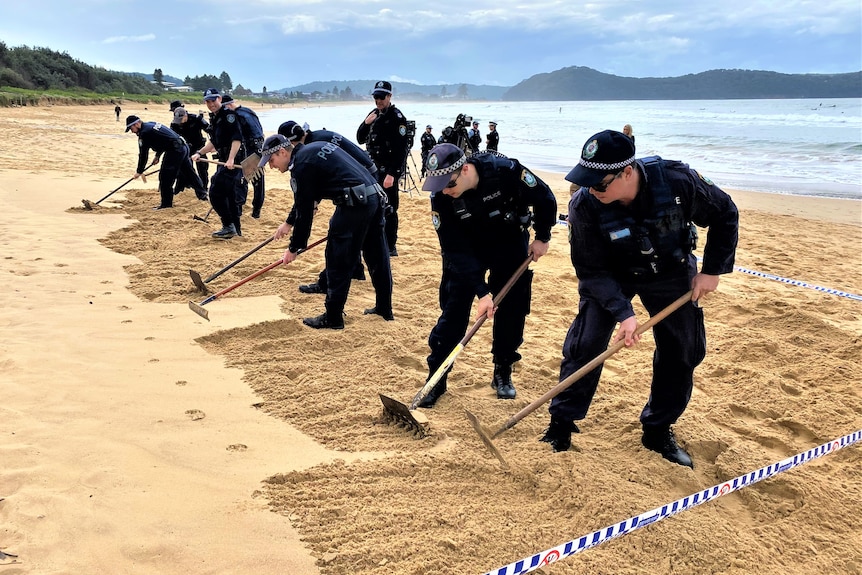 Police scouring a beach with rakes
