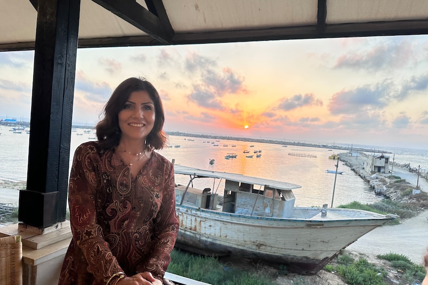 日落时分，一位女性站在一艘船前的阳台上。