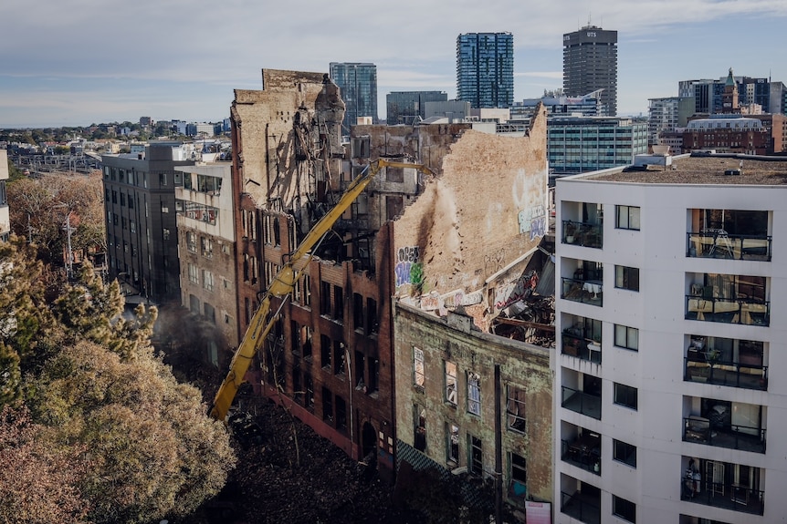 A crane smashes into a city building.