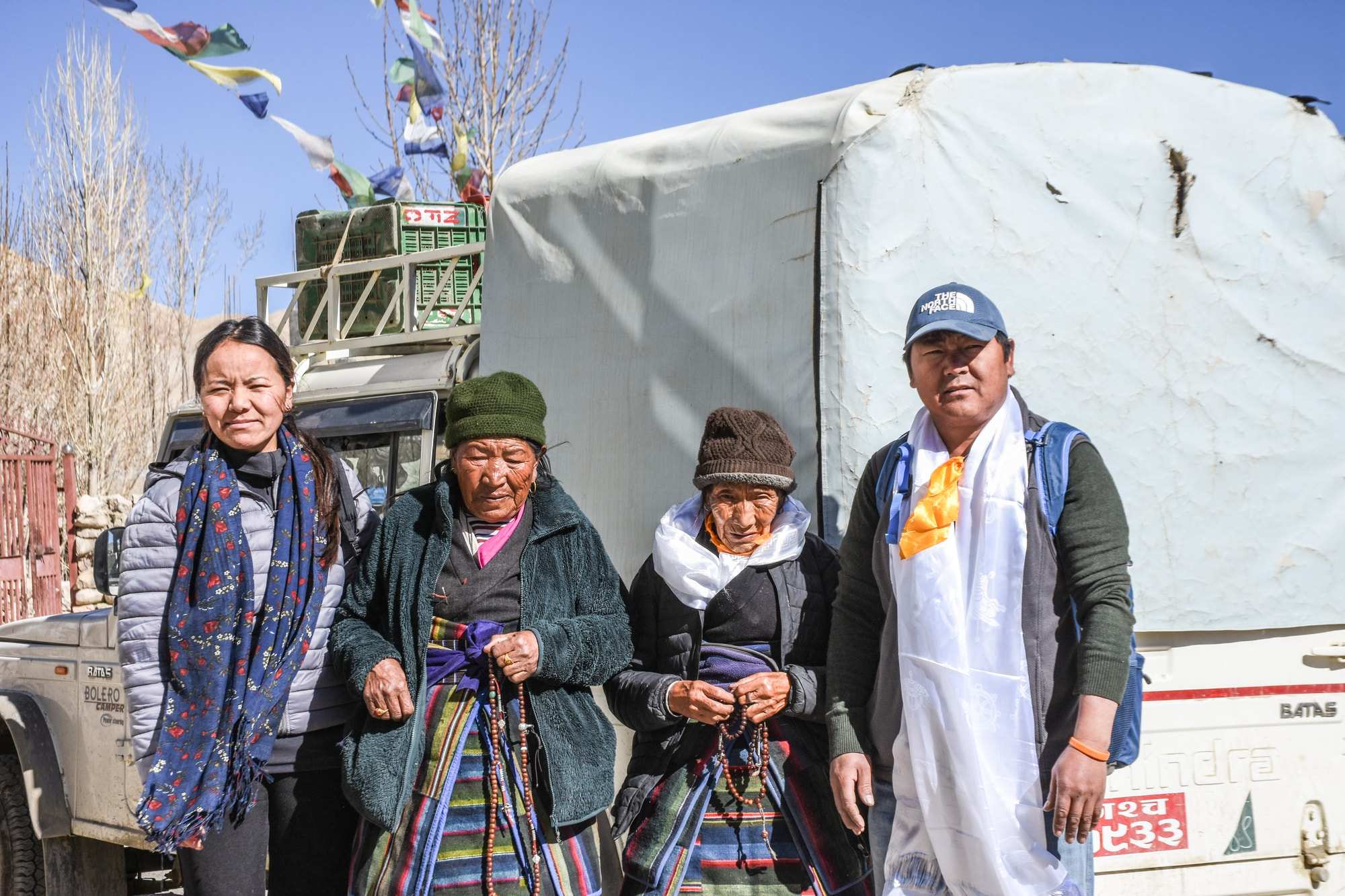 Two elderly woman and younger children stand before a van