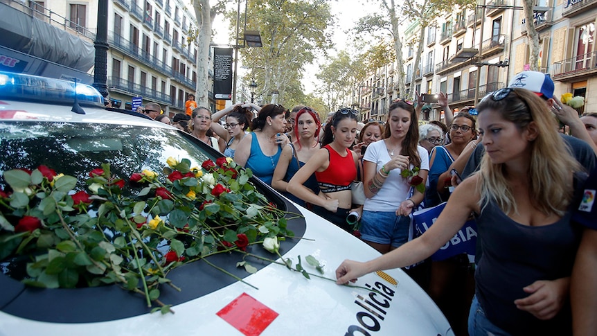 People lay flowers on a police car after an anti-violence march in Barcelona.
