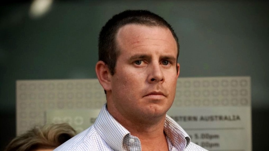 A close up photo of a man with short-cropped hair wearing an open shirt standing outside a court.