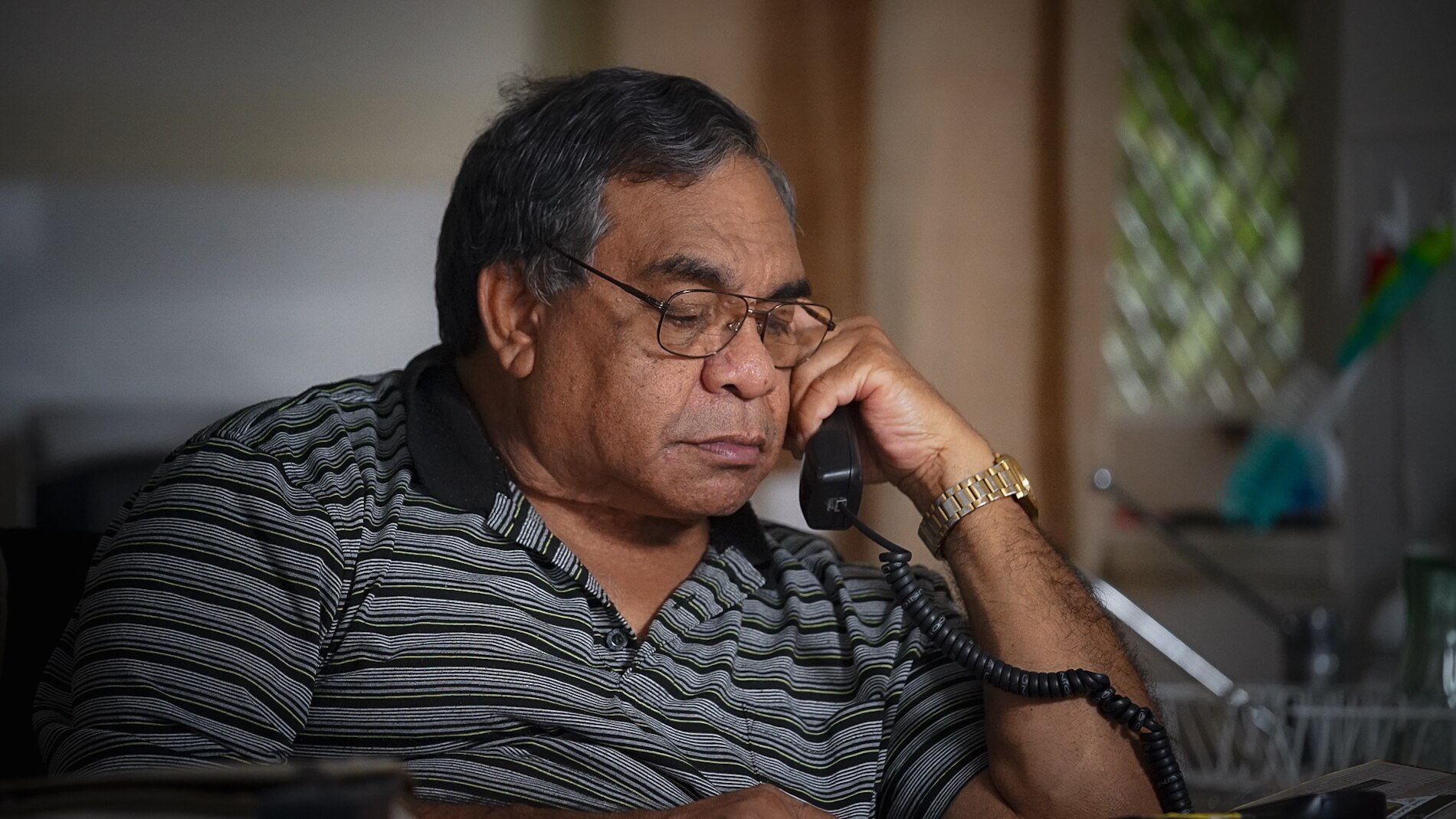 Homem olha para baixo enquanto segura o receptor do telefone na cabeça