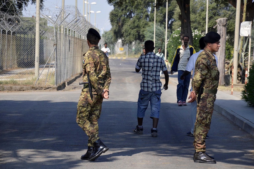 Soldiers are seen patrolling outside fences of the Isola di Capo Rizzuto migrant centre.