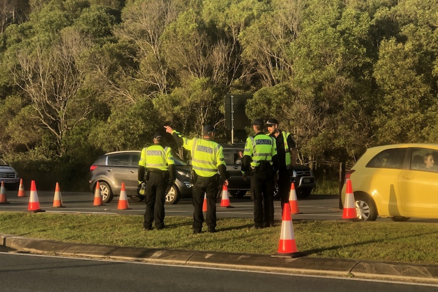 Police stand next to cars lined up on road