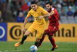 Australia's Tom Rogic runs with the ball as Syria's Tamer Mohamad challenges during the 2018 World Cup qualifying football match