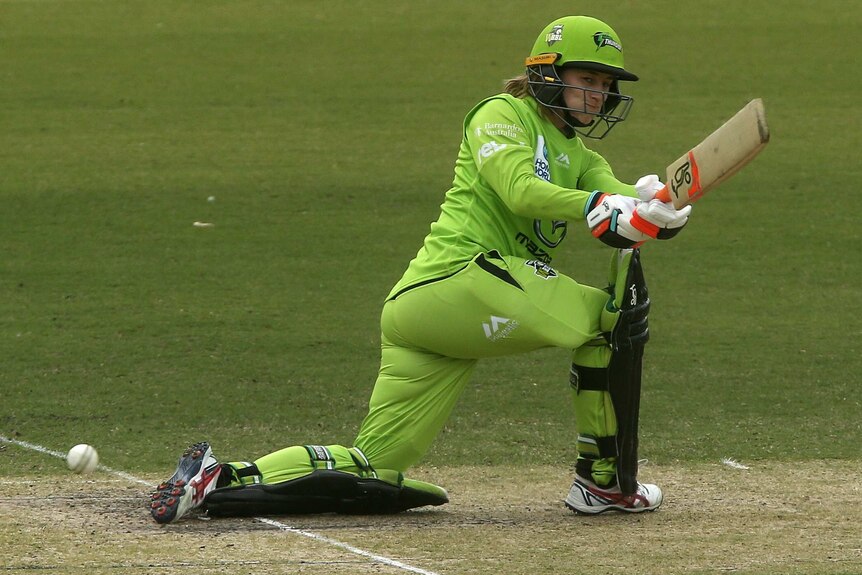 A Sydney Thunder WBBL player attempts a sweep shot against the Melbourne Renegades.